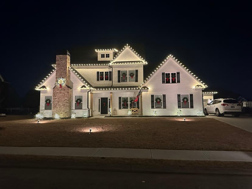 White house decorated with Christmas lights and wreaths at night. Holiday spirit.